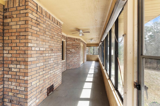 corridor with brick wall, concrete flooring, and ornamental molding