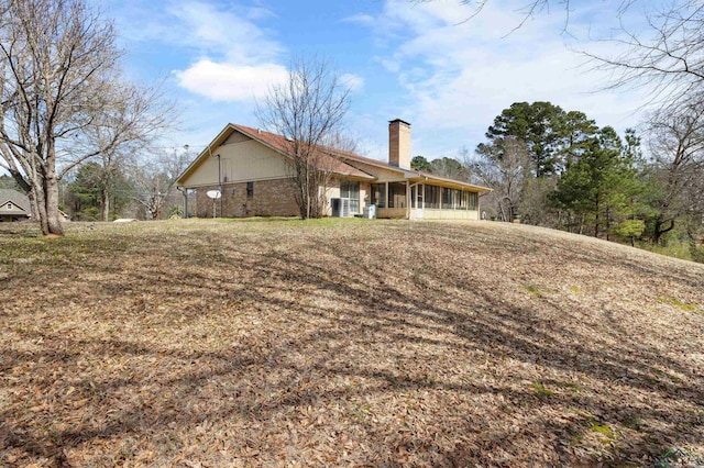 rear view of house featuring a chimney and a sunroom