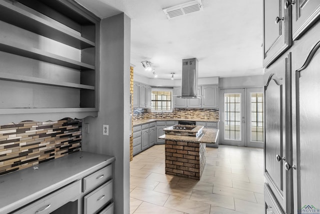 kitchen with tasteful backsplash, gray cabinetry, visible vents, and island range hood