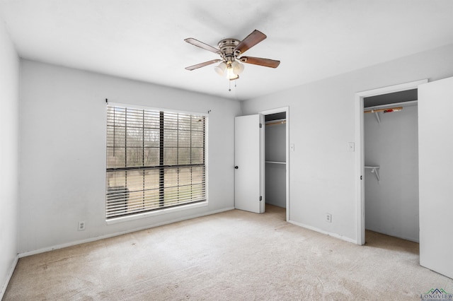 unfurnished bedroom with a ceiling fan, carpet, and two closets