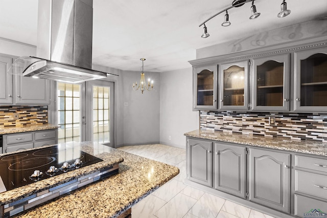 kitchen with marble finish floor, gray cabinets, glass insert cabinets, island range hood, and black electric cooktop