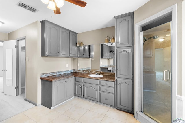 kitchen with dark countertops, visible vents, gray cabinetry, and light tile patterned floors