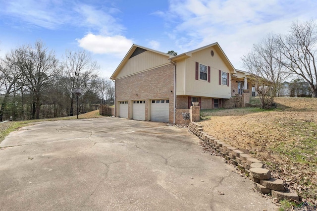 view of property exterior with a garage, brick siding, and driveway