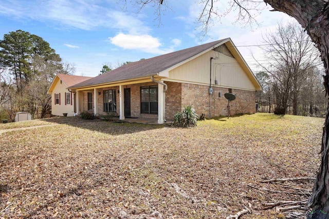 view of property exterior with a porch, a yard, and brick siding