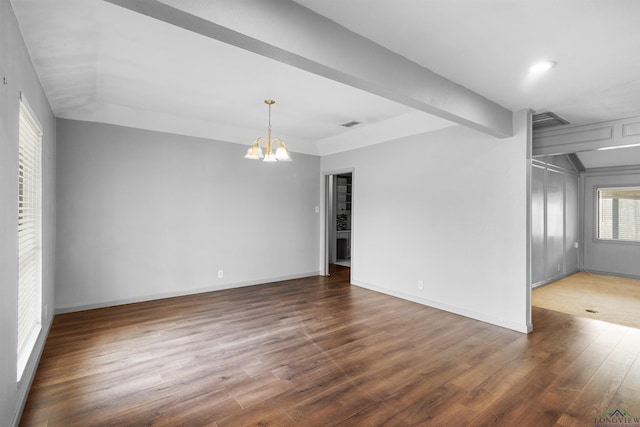 unfurnished room with a chandelier, lofted ceiling with beams, baseboards, and wood finished floors