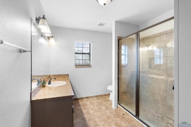 bathroom featuring visible vents, baseboards, toilet, a stall shower, and vanity