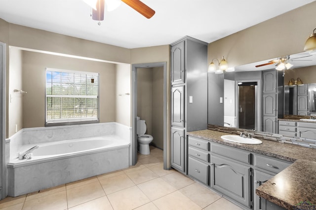 full bath featuring toilet, a garden tub, tile patterned floors, vanity, and a ceiling fan