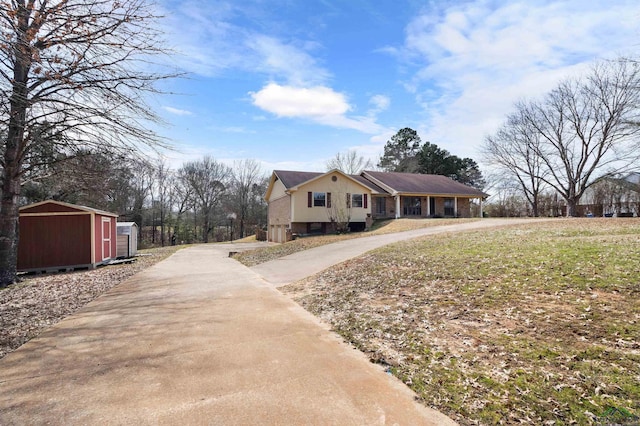 view of front of home featuring concrete driveway, an outbuilding, and a shed