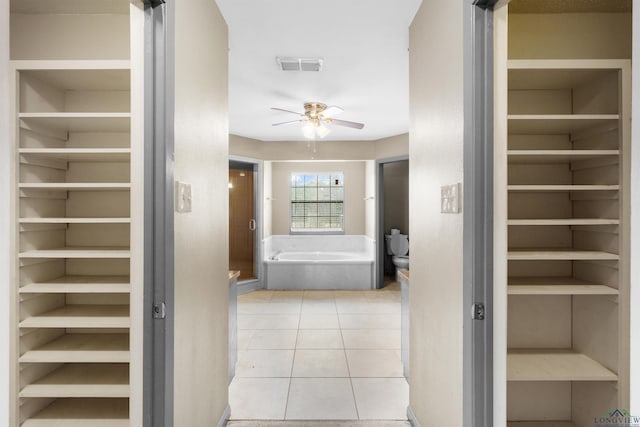 bathroom featuring tile patterned floors, a spacious closet, a ceiling fan, and visible vents