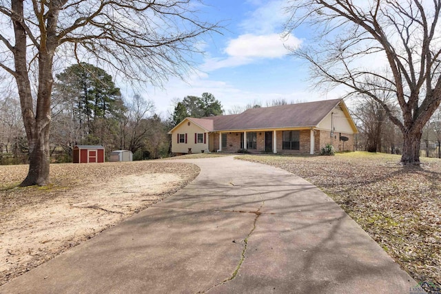 view of front of home featuring a storage unit, an outdoor structure, concrete driveway, and brick siding