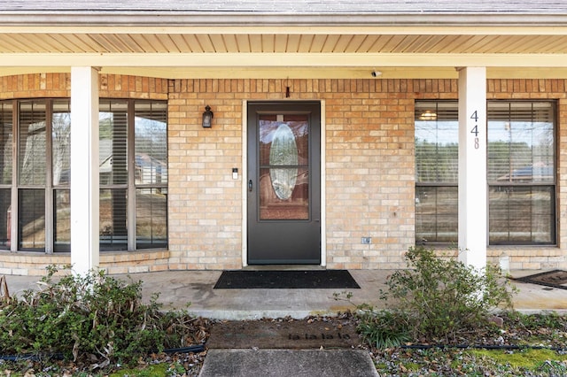 property entrance featuring brick siding and a porch