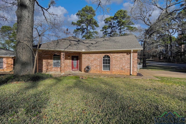 view of front of property with a shingled roof, a front lawn, and brick siding