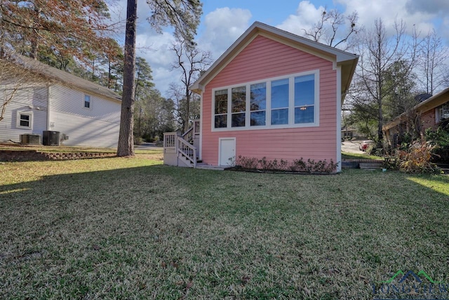 view of side of home featuring a yard and central AC