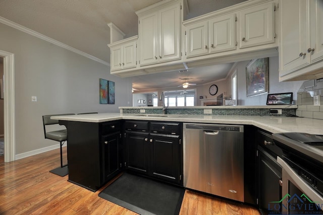 kitchen featuring a kitchen bar, sink, appliances with stainless steel finishes, kitchen peninsula, and white cabinets