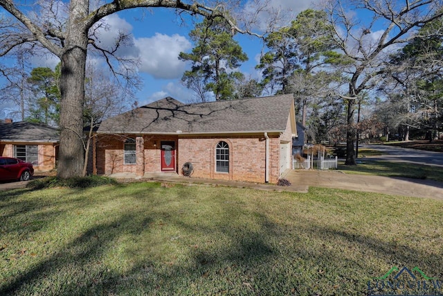 view of front facade featuring brick siding, a shingled roof, a front yard, and concrete driveway
