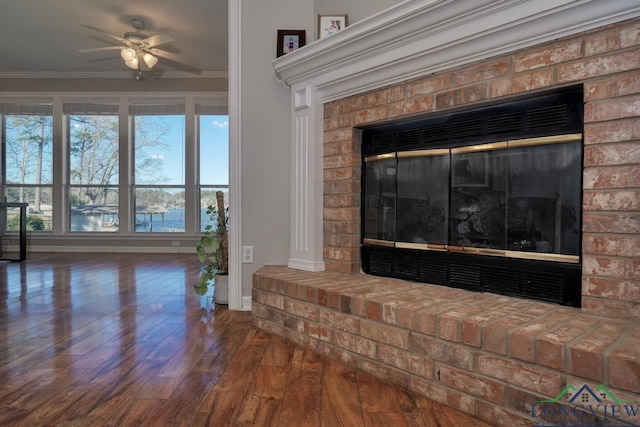 details with hardwood / wood-style flooring, a water view, ornamental molding, and a brick fireplace