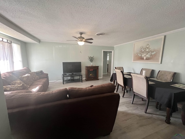 living room featuring crown molding, ceiling fan, carpet floors, and a textured ceiling