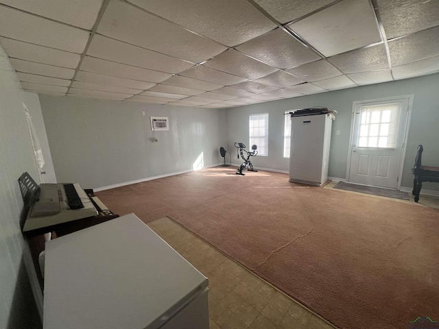 exercise area featuring a wall mounted air conditioner, plenty of natural light, carpet flooring, and a paneled ceiling