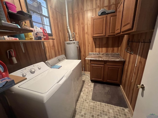 laundry area featuring cabinets, wooden walls, washer and dryer, and gas water heater