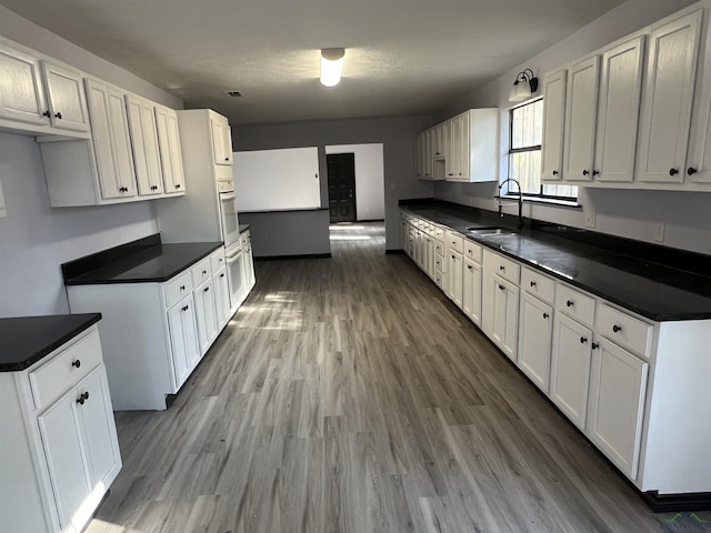 kitchen featuring white cabinets, white oven, and sink