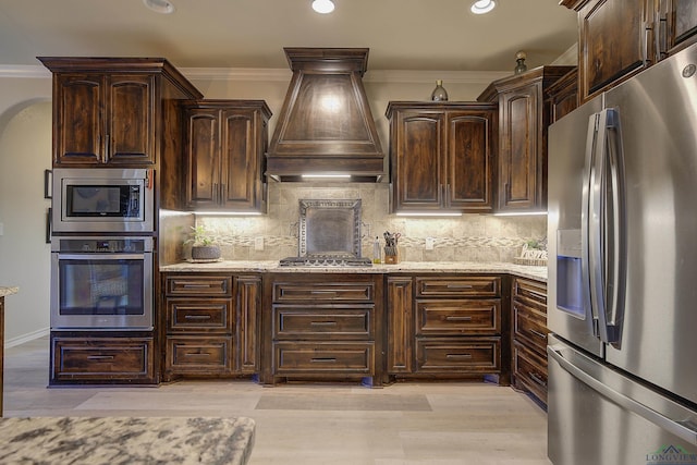 5112 Remington St, Texarkana, TX 75503 - kitchen with stainless steel appliances, custom exhaust hood, dark brown cabinetry, light stone counters, and tasteful backsplash