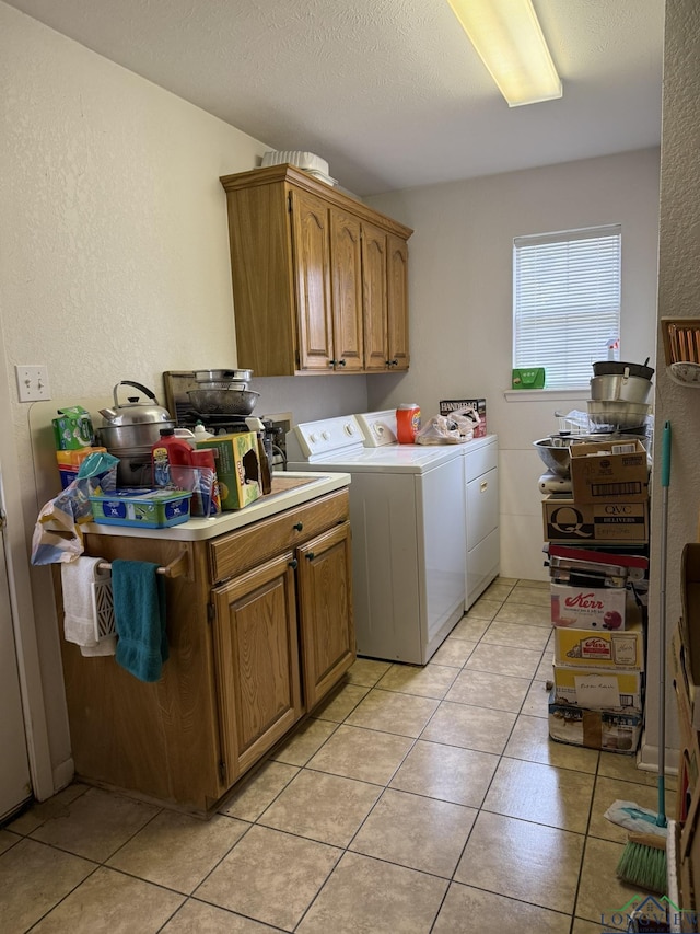 laundry area featuring separate washer and dryer, light tile patterned floors, cabinets, and a textured ceiling