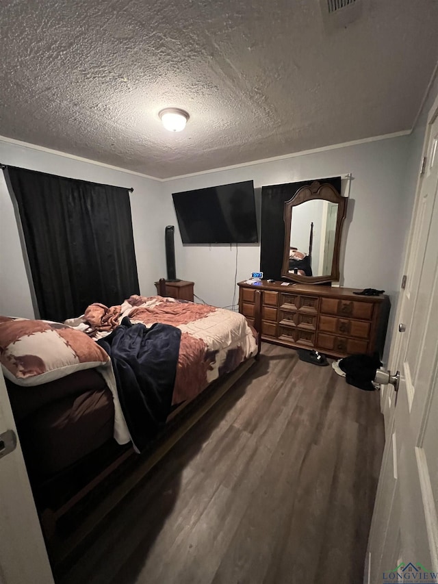 bedroom with wood-type flooring, a textured ceiling, and ornamental molding