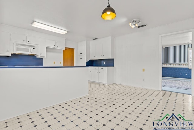 kitchen with decorative light fixtures and white cabinetry