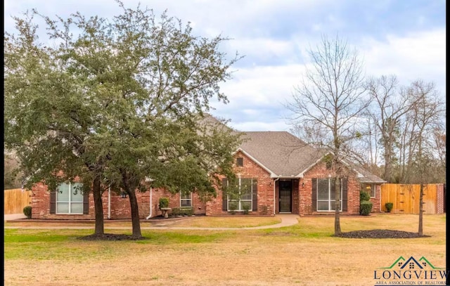 view of front facade featuring brick siding, fence, and a front lawn