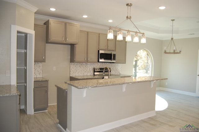 kitchen featuring tasteful backsplash, light stone countertops, hanging light fixtures, and stainless steel appliances