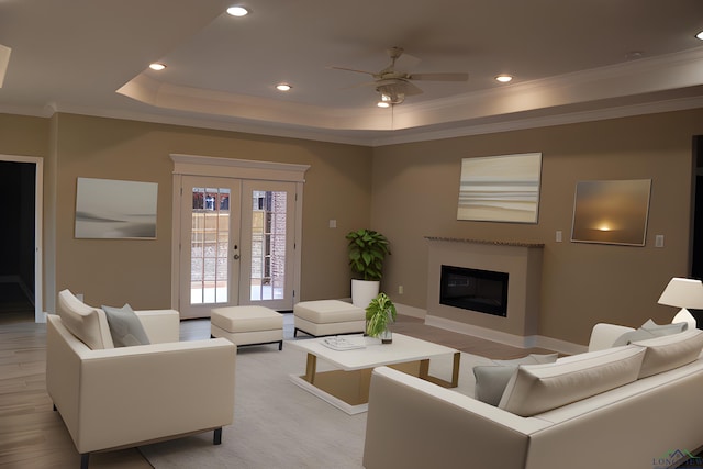 living room featuring french doors, light wood-type flooring, ornamental molding, a tray ceiling, and ceiling fan