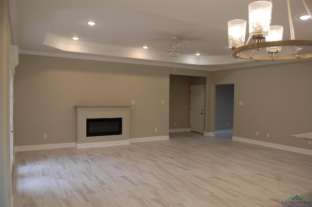 unfurnished living room with ornamental molding, a tray ceiling, ceiling fan, and light hardwood / wood-style floors