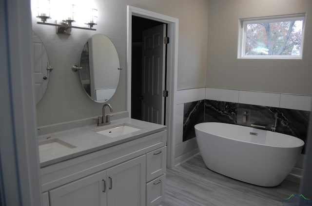 bathroom featuring a bathing tub, vanity, and tile walls