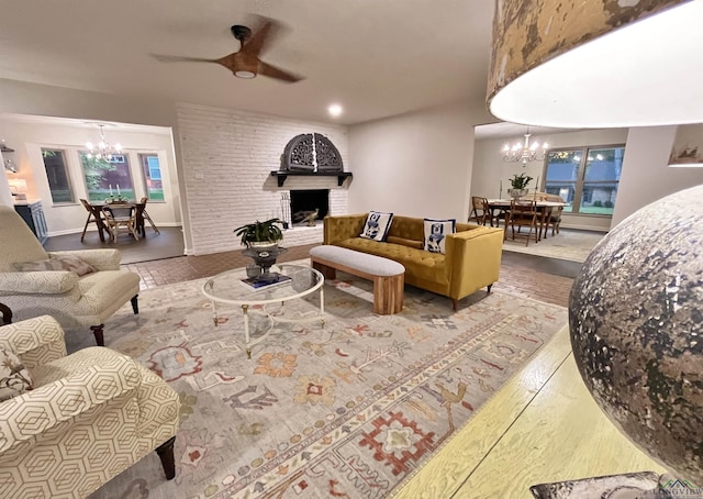 living room featuring a fireplace, wood-type flooring, and ceiling fan with notable chandelier