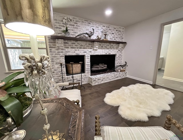 living room featuring dark wood-type flooring and a brick fireplace