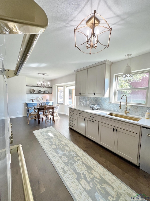 kitchen featuring decorative backsplash, gray cabinets, hanging light fixtures, and sink