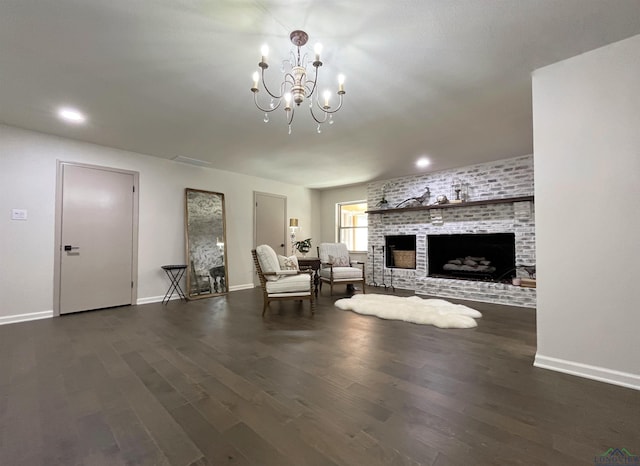 unfurnished living room with a chandelier, a brick fireplace, and dark wood-type flooring