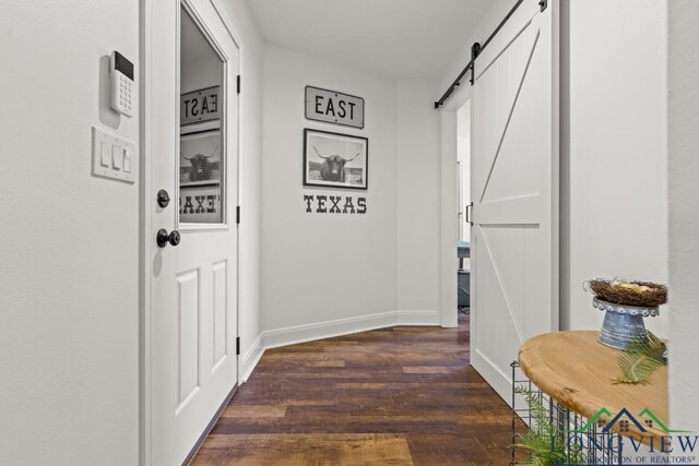 6056 Bobwhite Rd, Gilmer, TX 75645 - doorway with a barn door, dark wood-style flooring, and baseboards