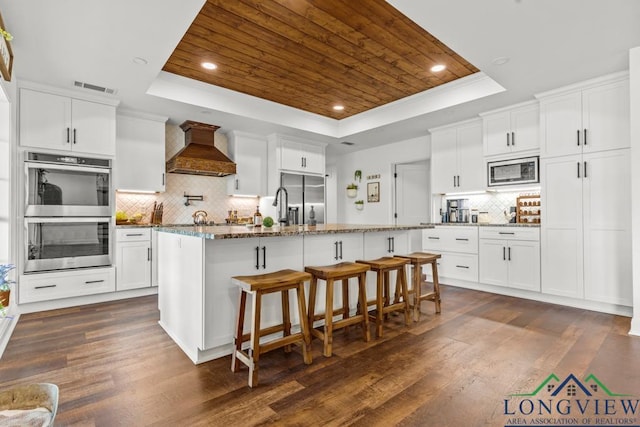 6056 Bobwhite Rd, Gilmer, TX 75645 - kitchen with a raised ceiling, built in appliances, custom exhaust hood, wooden ceiling, and decorative backsplash