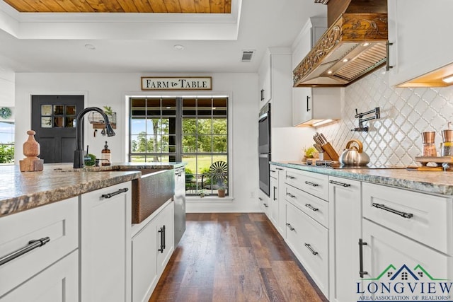 6056 Bobwhite Rd, Gilmer, TX 75645 - kitchen with custom range hood, a raised ceiling, healthy amount of natural light, decorative backsplash, and ornamental molding