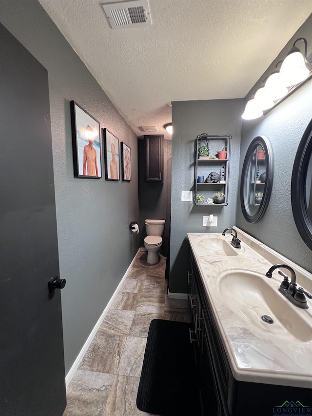 bathroom featuring vanity, a textured ceiling, and toilet