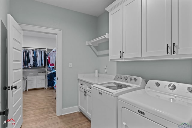 laundry area featuring cabinets, washing machine and dryer, and light hardwood / wood-style flooring