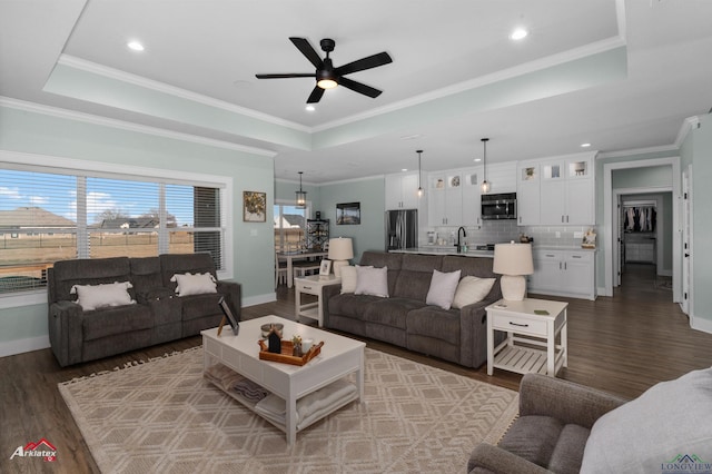 living room featuring a tray ceiling, ceiling fan, dark hardwood / wood-style flooring, and crown molding