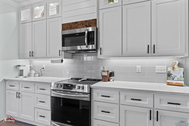 kitchen with white cabinets, appliances with stainless steel finishes, backsplash, and light stone countertops