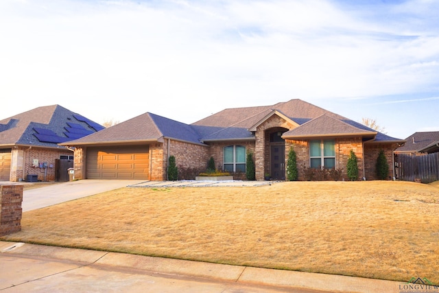 view of front of house featuring a shingled roof, a front yard, fence, a garage, and driveway