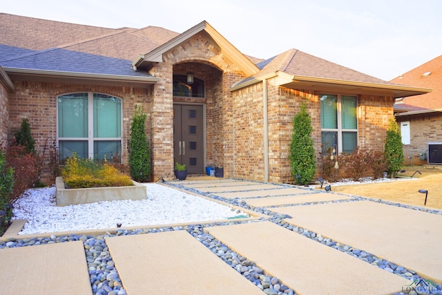 view of front of house featuring a shingled roof and brick siding