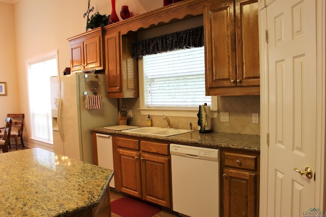 kitchen with light stone countertops, sink, white appliances, and backsplash