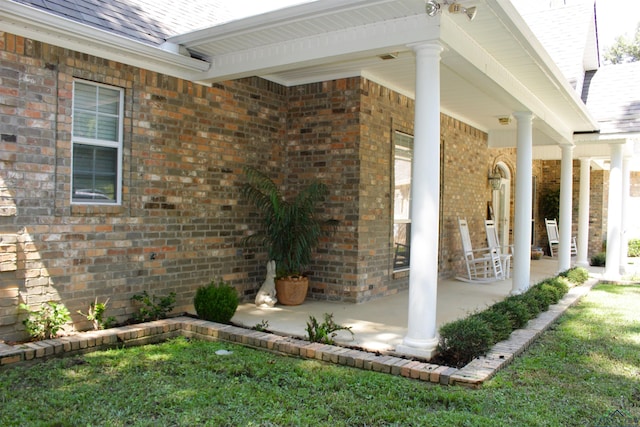 doorway to property featuring a porch and a yard