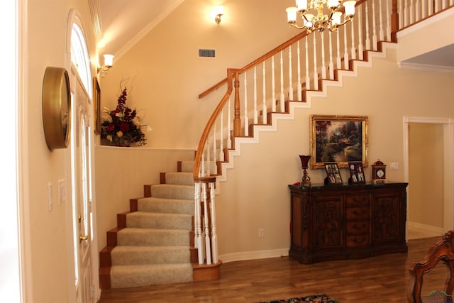 stairs featuring hardwood / wood-style floors, ornamental molding, a high ceiling, and a chandelier