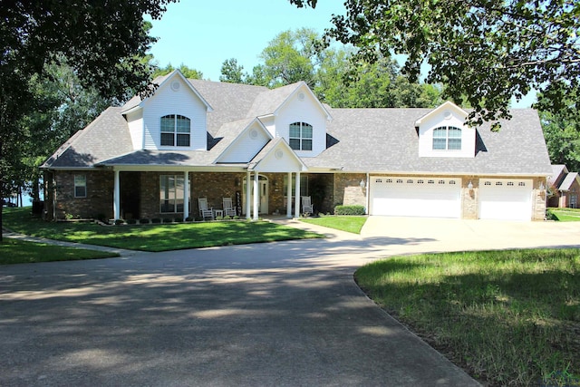 view of front of home featuring covered porch, a garage, and a front lawn